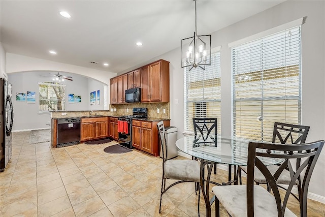 kitchen with a peninsula, a sink, backsplash, ceiling fan with notable chandelier, and black appliances