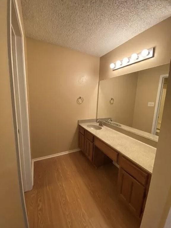1202 Thorpe Ln Unit 211, San Marcos, TX 78666 - bathroom featuring vanity, baseboards, a textured ceiling, and wood finished floors