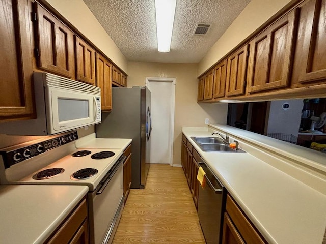1202 Thorpe Ln Unit 211, San Marcos, TX 78666 - kitchen featuring appliances with stainless steel finishes, a sink, light countertops, light wood-style flooring, and visible vents
