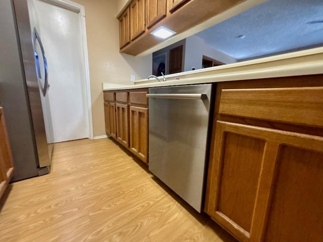 1202 Thorpe Ln Unit 211, San Marcos, TX 78666 - kitchen with light countertops, stainless steel appliances, brown cabinetry, and light wood-style floors