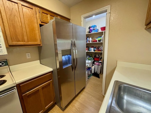 1202 Thorpe Ln Unit 211, San Marcos, TX 78666 - kitchen featuring white electric range, light countertops, light wood-type flooring, brown cabinets, and stainless steel fridge with ice dispenser