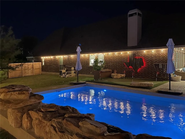 pool at twilight featuring fence, an outdoor pool, and a patio