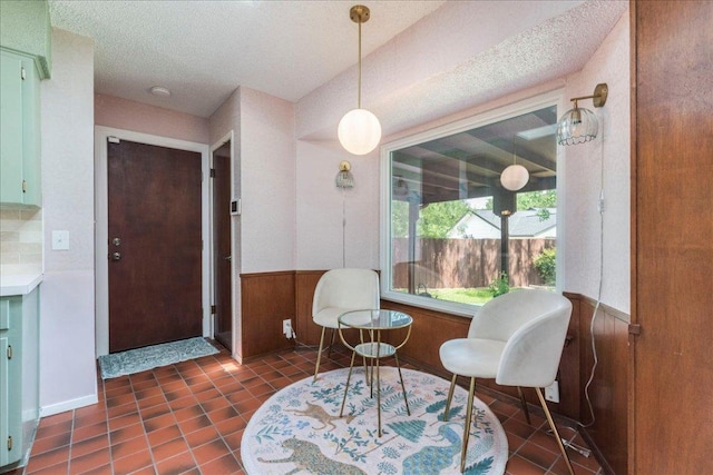 9011 W Pointer Ln, Austin, TX 78758 - sitting room featuring a textured ceiling, a wainscoted wall, dark tile patterned floors, and wooden walls