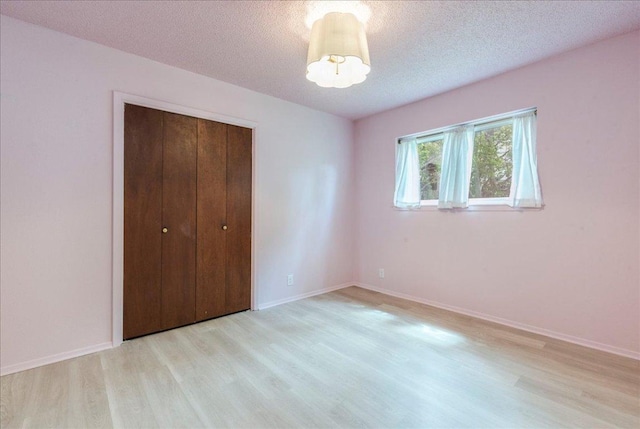 9011 W Pointer Ln, Austin, TX 78758 - unfurnished bedroom with light wood-style floors, a closet, a textured ceiling, and baseboards