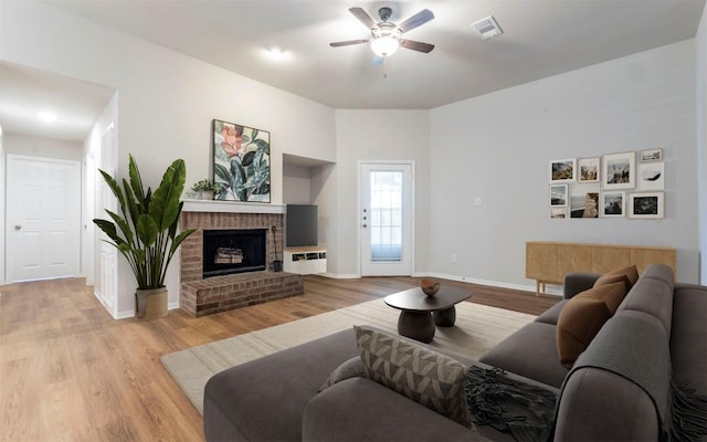 208 Bastian Ln, Georgetown, TX 78626 - living area with a ceiling fan, light wood-style flooring, a brick fireplace, and baseboards