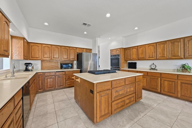 3225 Eisenhower Ave, Lago Vista, TX 78645 - kitchen featuring black appliances, a sink, brown cabinetry, a center island, and light tile patterned floors