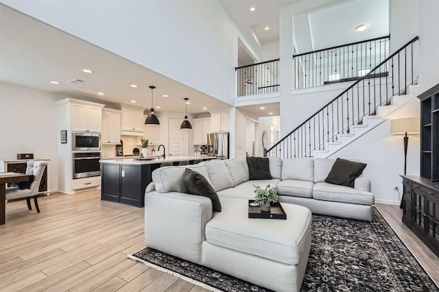 1205 Bluewood Bnd, Leander, TX 78641 - living room with light wood-style flooring, stairs, a high ceiling, recessed lighting, and baseboards