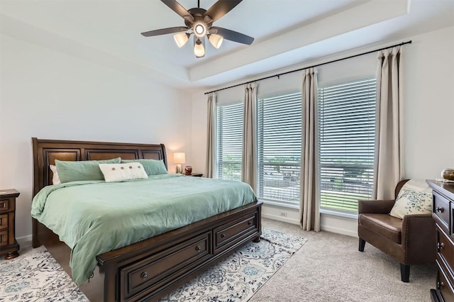 1205 Bluewood Bnd, Leander, TX 78641 - bedroom featuring a tray ceiling, multiple windows, light carpet, and ceiling fan