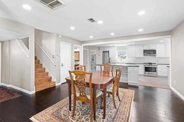 dining room with dark wood-type flooring, stairway, baseboards, and recessed lighting