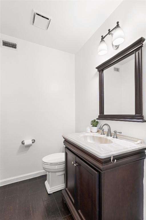 half bath with toilet, vanity, and baseboards