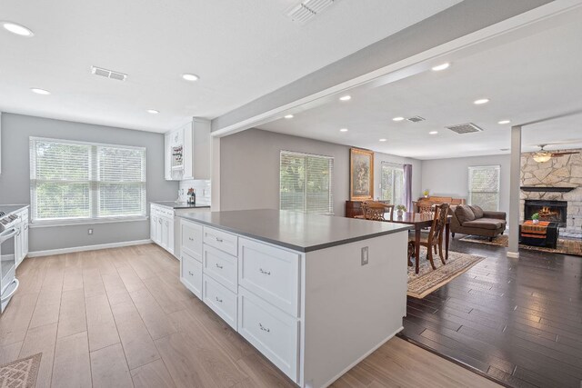 kitchen with wood finished floors, white cabinets, baseboards, dark countertops, and a fireplace