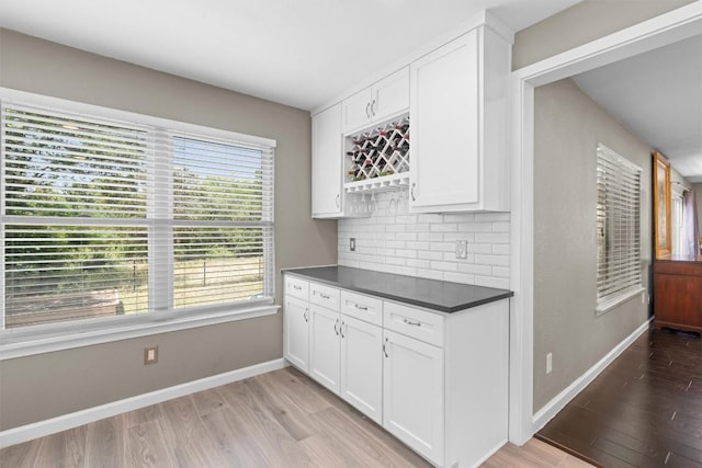 kitchen featuring light wood-type flooring, dark countertops, baseboards, and tasteful backsplash