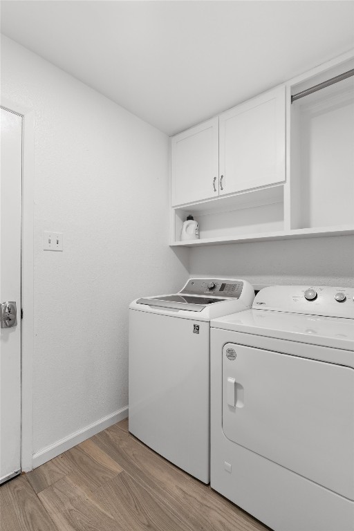 washroom with washer and clothes dryer, cabinet space, light wood-type flooring, and baseboards