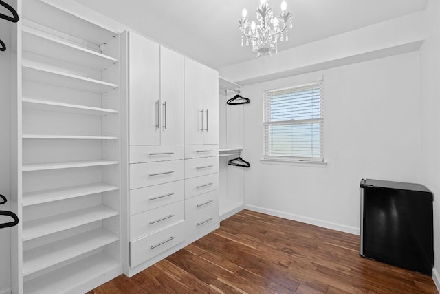 spacious closet with dark wood-style floors and a chandelier