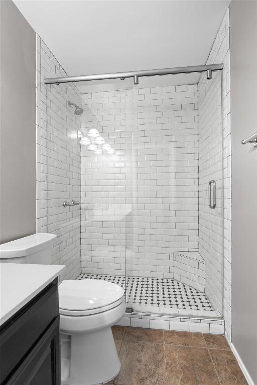 bathroom with toilet, vanity, a shower stall, and tile patterned floors