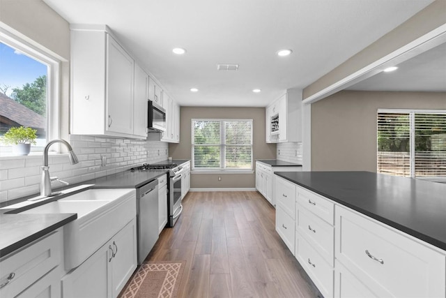 kitchen with stainless steel appliances, dark wood-style flooring, baseboards, recessed lighting, and white cabinetry