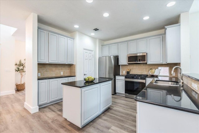 kitchen featuring a sink, dark countertops, visible vents, decorative backsplash, and appliances with stainless steel finishes
