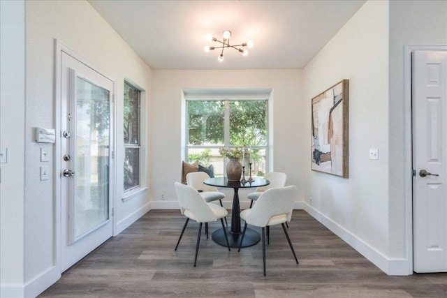 dining area featuring dark wood finished floors, baseboards, and a notable chandelier