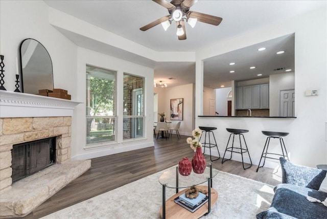 living room featuring baseboards, recessed lighting, wood finished floors, ceiling fan, and a fireplace