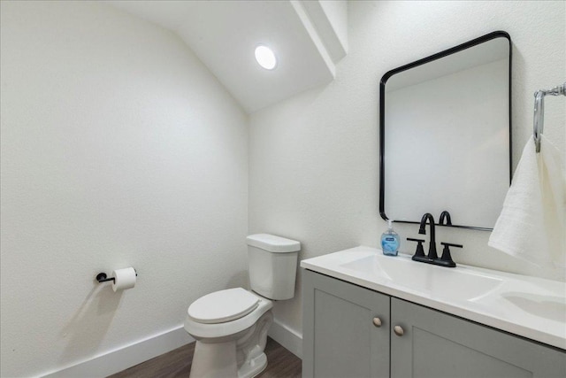 bathroom with lofted ceiling, baseboards, wood finished floors, and toilet