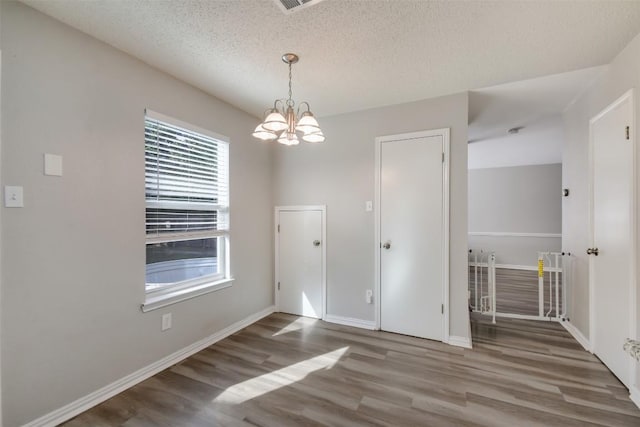 1320 Green Terrace Dr, Round Rock, TX 78664 - unfurnished dining area with baseboards, a chandelier, wood finished floors, and a textured ceiling