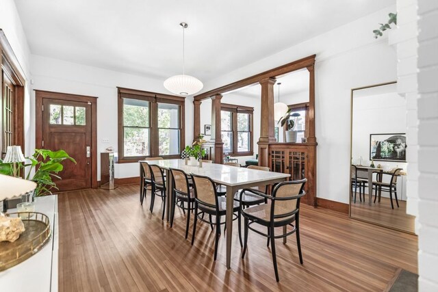 dining room featuring baseboards, wood finished floors, and decorative columns