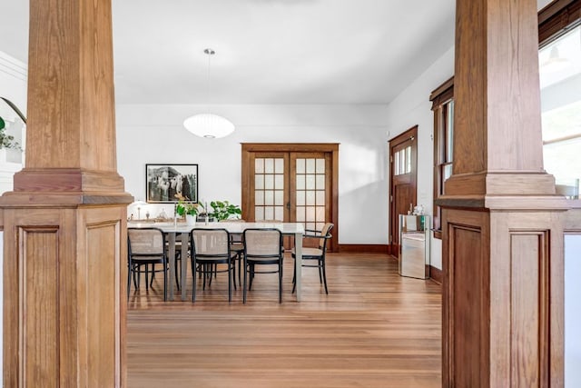 dining area with light wood finished floors, baseboards, and decorative columns