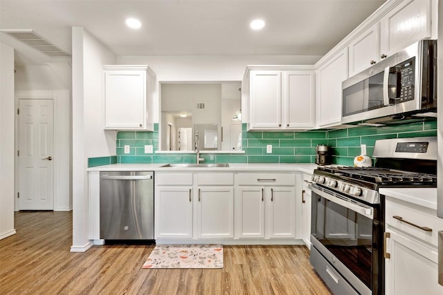 3116 Port Anne Way, Leander, TX 78641 - kitchen with stainless steel appliances, light wood-style flooring, a sink, light countertops, and white cabinetry