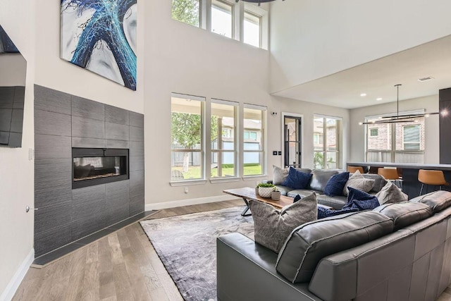 15500 La Catania Way, Austin, TX 78738 - living room with plenty of natural light, baseboards, light wood-type flooring, a tile fireplace, and a high ceiling