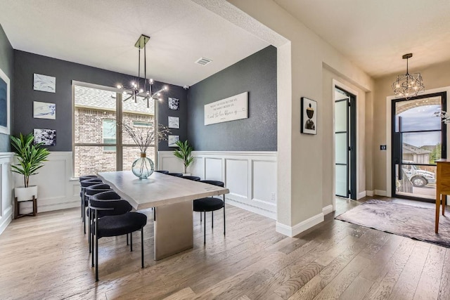 15500 La Catania Way, Austin, TX 78738 - dining area with a chandelier, a decorative wall, hardwood / wood-style flooring, and wainscoting