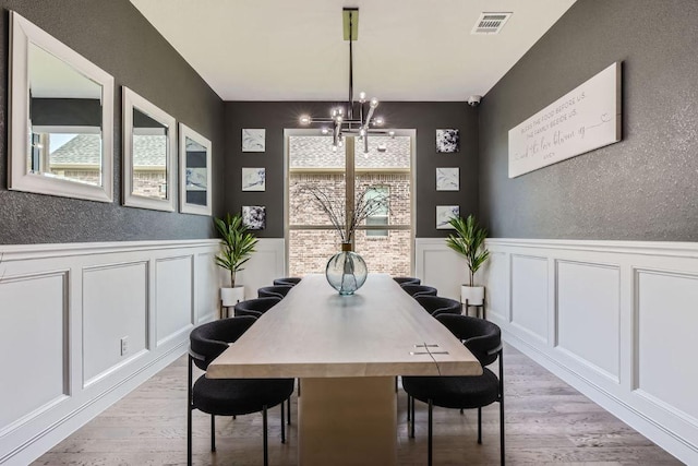15500 La Catania Way, Austin, TX 78738 - dining area featuring a decorative wall, wainscoting, light wood finished floors, and a chandelier