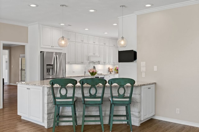 2409 Mormon Mill Rd, Marble Falls, TX 78654 - kitchen with tasteful backsplash, under cabinet range hood, stainless steel fridge, white cabinets, and ornamental molding