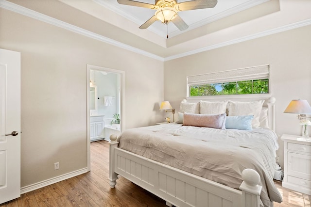 2409 Mormon Mill Rd, Marble Falls, TX 78654 - bedroom featuring connected bathroom, ornamental molding, wood finished floors, and a tray ceiling