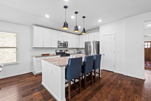 11928 Arran St, Austin, TX 78754 - kitchen with stainless steel appliances, a kitchen breakfast bar, an island with sink, dark wood-style flooring, and light stone countertops