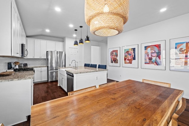 11928 Arran St, Austin, TX 78754 - kitchen with appliances with stainless steel finishes, backsplash, light stone countertops, a center island with sink, and white cabinetry