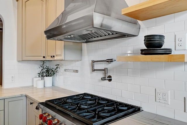 kitchen featuring exhaust hood, tasteful backsplash, arched walkways, stovetop, and light stone counters