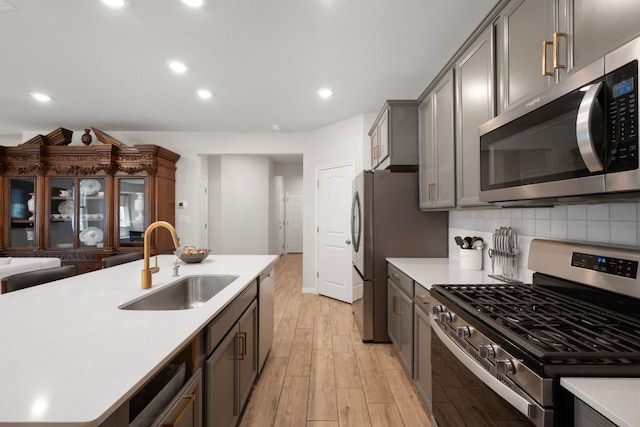 1921 Winston Way, Leander, TX 78641 - kitchen featuring stainless steel appliances, light wood-style flooring, light countertops, gray cabinets, and tasteful backsplash