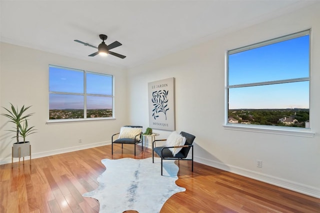 sitting room with a ceiling fan, baseboards, a healthy amount of sunlight, and wood finished floors
