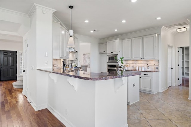 12400 Fairfax Ridge Pl, Austin, TX 78738 - kitchen with appliances with stainless steel finishes, ornamental molding, a breakfast bar, a peninsula, and backsplash