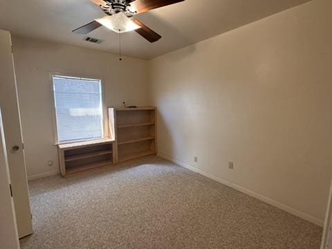 carpeted empty room featuring baseboards, a ceiling fan, and visible vents