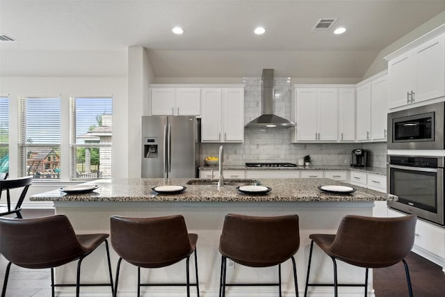 624 Anfield Cir, Austin, TX 78738 - kitchen with appliances with stainless steel finishes, wall chimney range hood, a sink, white cabinets, and a kitchen bar