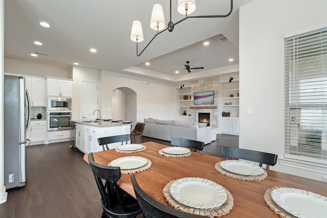 624 Anfield Cir, Austin, TX 78738 - dining space with arched walkways, dark wood-style flooring, a stone fireplace, recessed lighting, and built in shelves