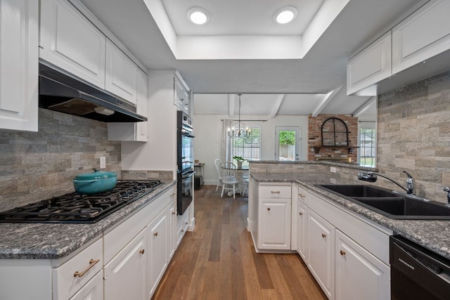 1314 Quailfield Cir, Austin, TX 78758 - kitchen with black appliances, under cabinet range hood, wood finished floors, white cabinetry, and a peninsula