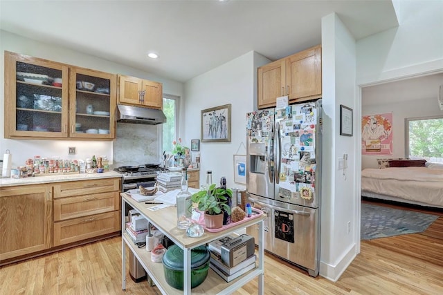 809 E 44th St, Austin, TX 78751 - kitchen featuring stainless steel appliances, under cabinet range hood, light wood-type flooring, glass insert cabinets, and light brown cabinets