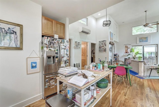 809 E 44th St, Austin, TX 78751 - kitchen with stainless steel fridge, a towering ceiling, a wall mounted air conditioner, light wood-type flooring, and a ceiling fan