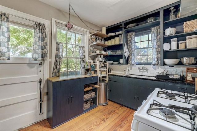 809 E 44th St, Austin, TX 78751 - kitchen featuring open shelves, white gas range oven, light wood-style floors, a sink, and backsplash