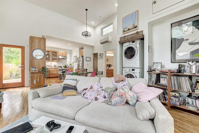 809 E 44th St, Austin, TX 78751 - living room with stacked washer / dryer, a wall mounted air conditioner, light wood-type flooring, a high ceiling, and recessed lighting