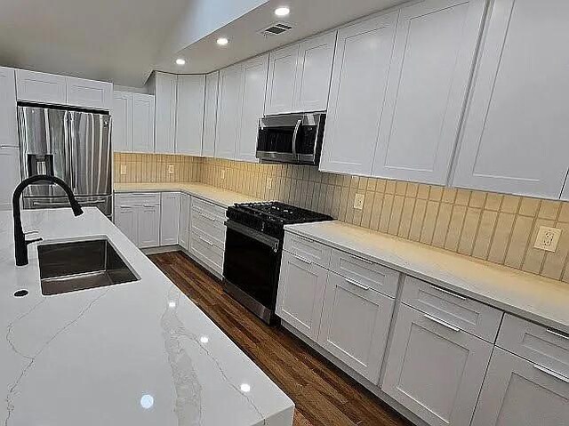 kitchen with white cabinets, backsplash, visible vents, a sink, and appliances with stainless steel finishes