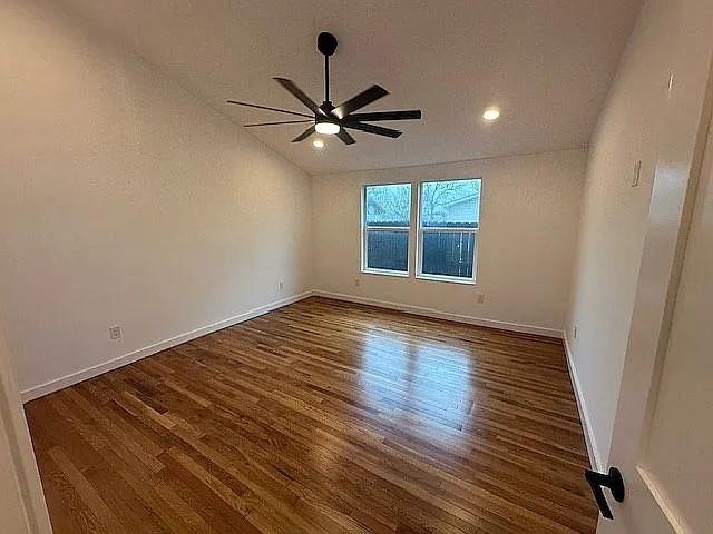 empty room featuring baseboards, a ceiling fan, wood finished floors, and vaulted ceiling