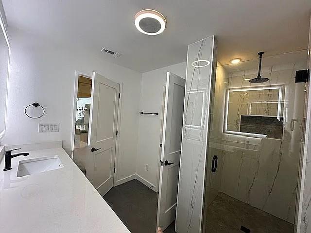 bathroom with visible vents, a sink, and a stall shower